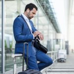 Businessman at airport, looking on watch