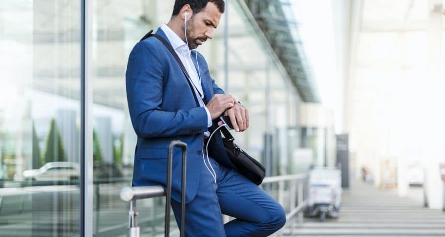 Businessman at airport, looking on watch