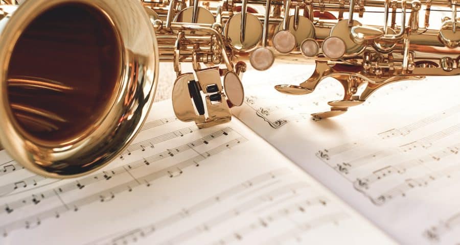 Closeup of a beautiful and shiny golden saxophone lying on music notes