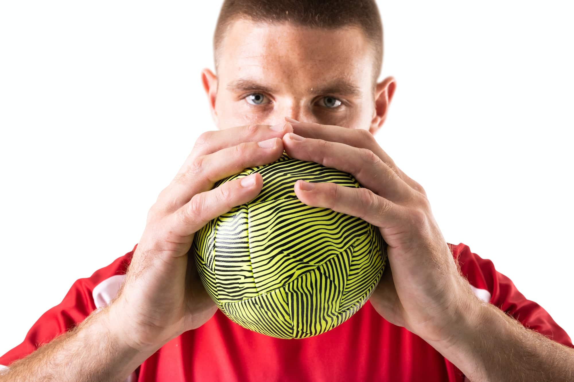 Confident young male caucasian handball player holding green ball against white background