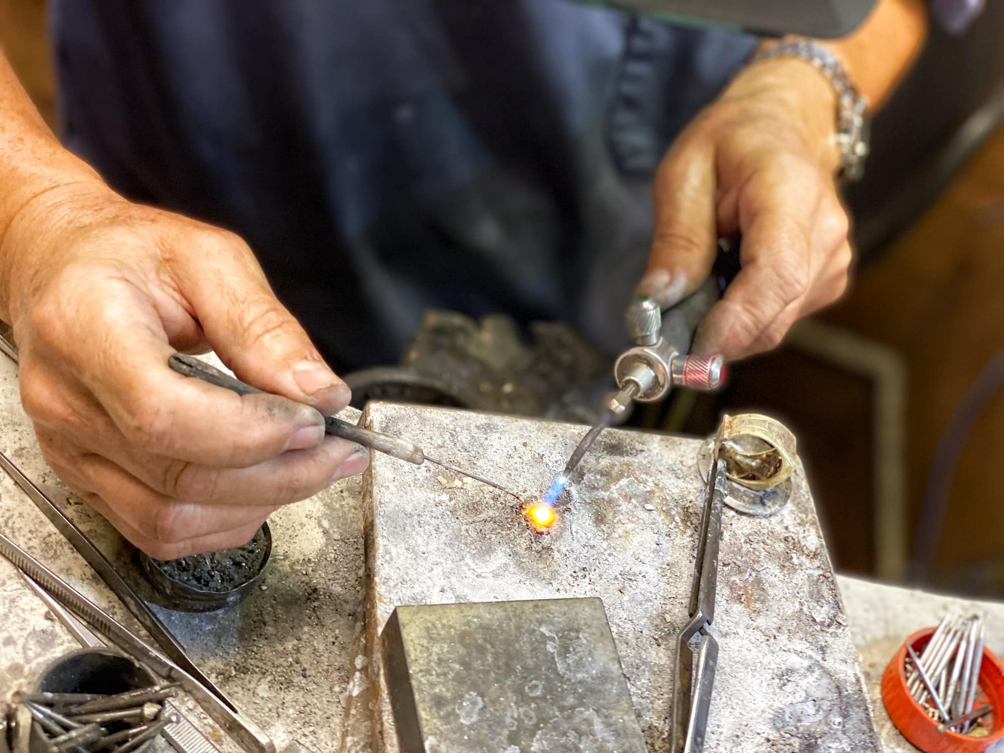 Goldsmith works on repairing a gold ring with a 900 degree(f) propane flame