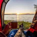 Man camping in Estonia, watching sunset lying in tent