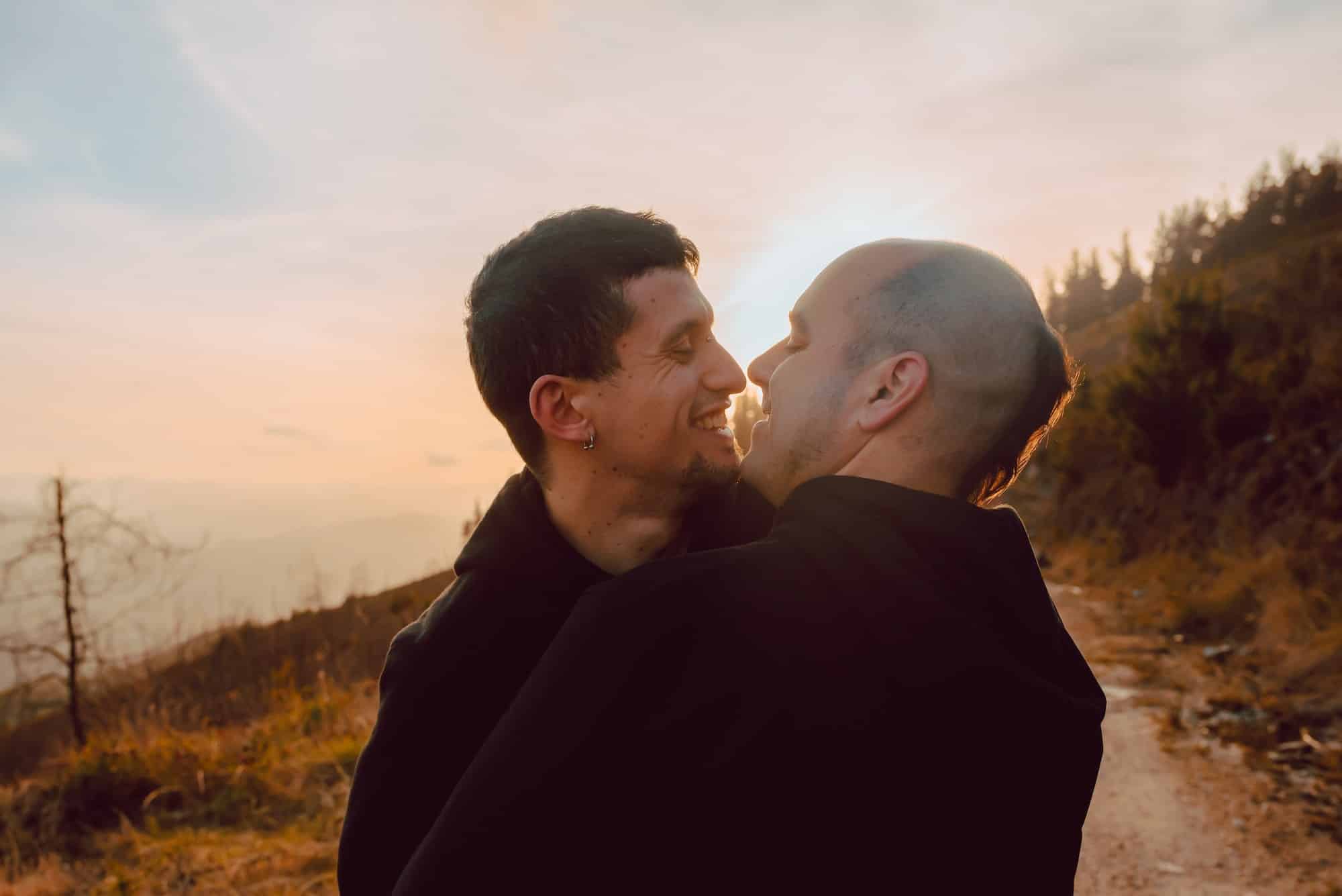 Men hugging and kissing in forest