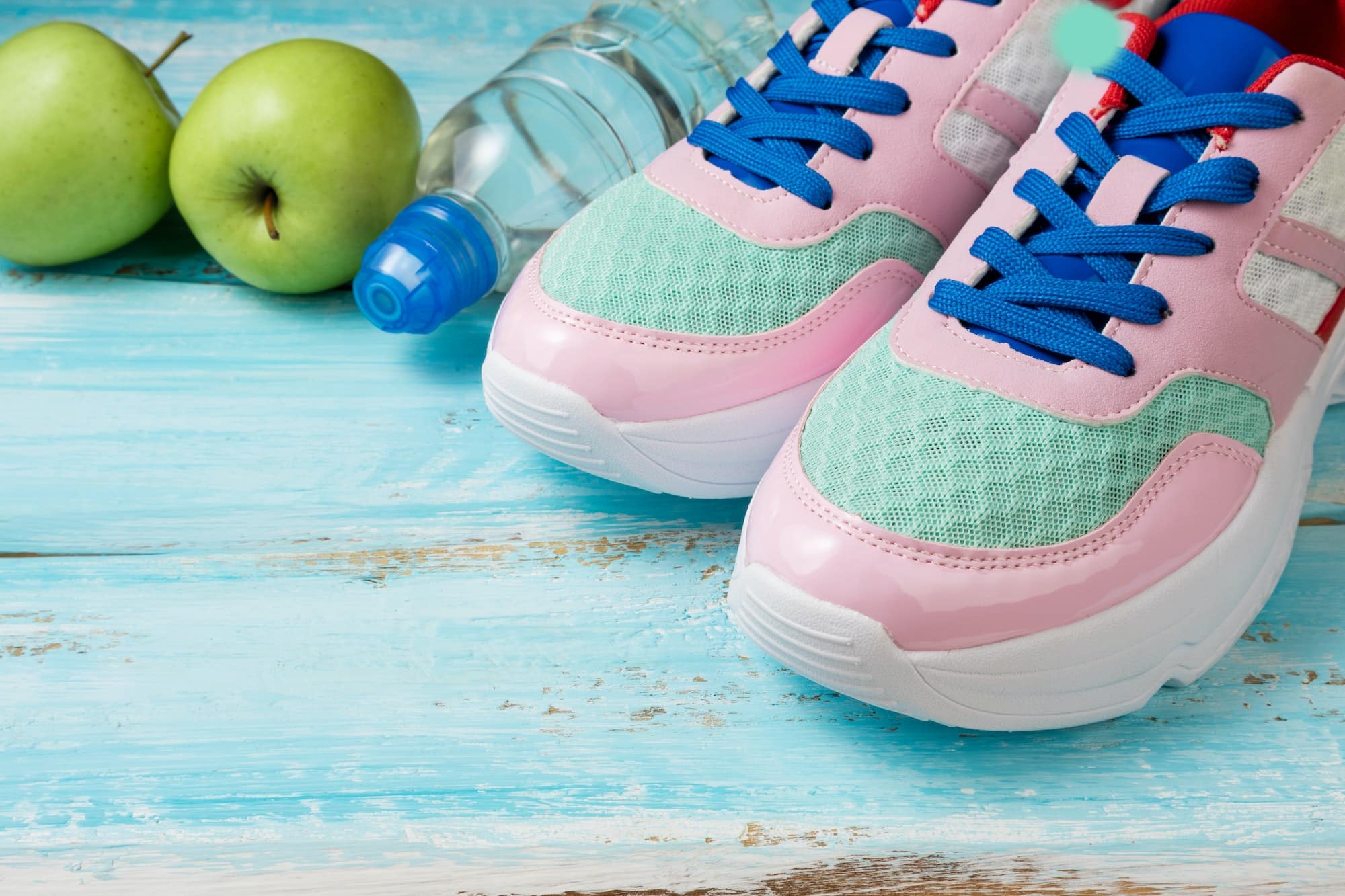 Pink sport shoes, bottle of water and green apples. Sport, healthy lifestyle, dieting