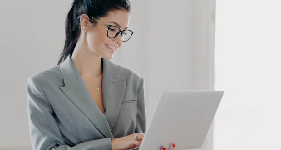 Self confident cheerful woman economist analyzes report about company income on laptop computer
