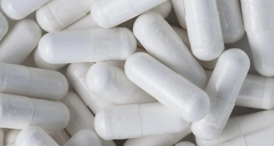 Top view Closeup pile of white antibiotic capsule pills texture. Pharmaceutical production industry
